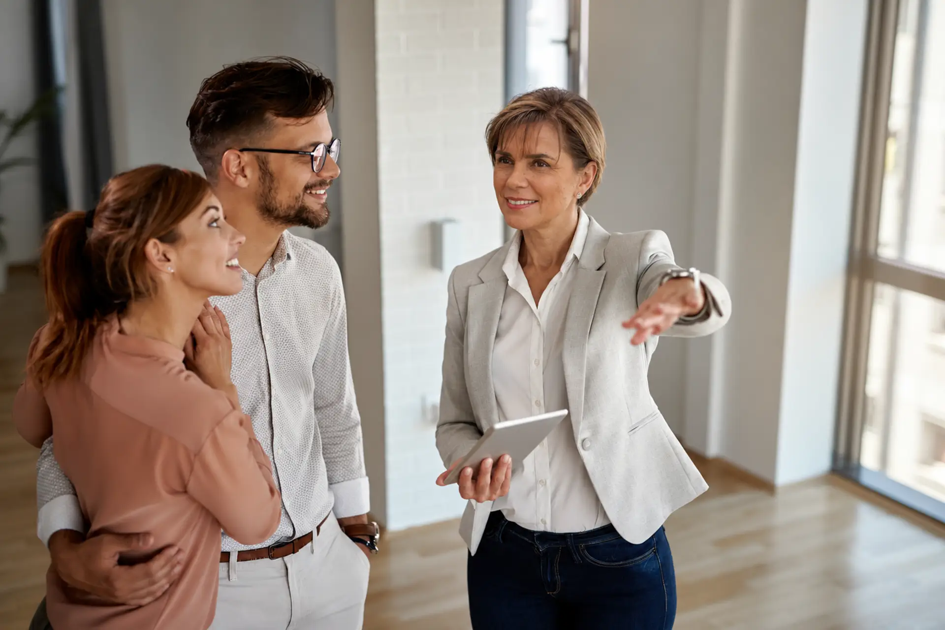 Ejecutiva inmobiliaria asesorando a una pareja en un departamento
